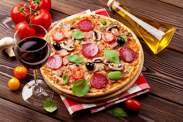 cuisine italienne pizza, pepperoni, tomates, d'olives, de basilic et rouge wi - salami sausage portion decoration photos et images de collection