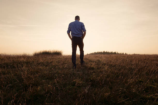 istock Man walking in the countryside looking at the sunset 490751178