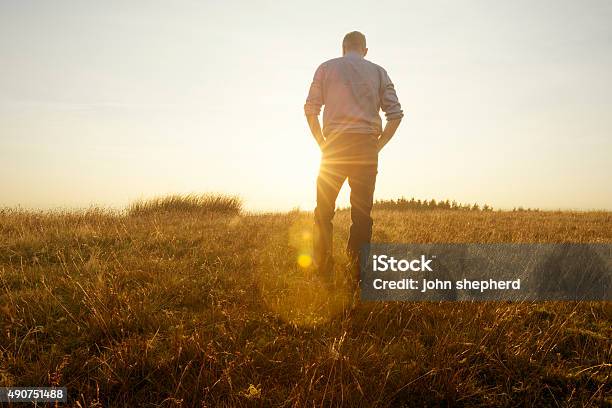 Man Walking In The Countryside Looking At The Sunset Stock Photo - Download Image Now