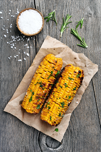 Grilled corn cobs on wooden background, top view