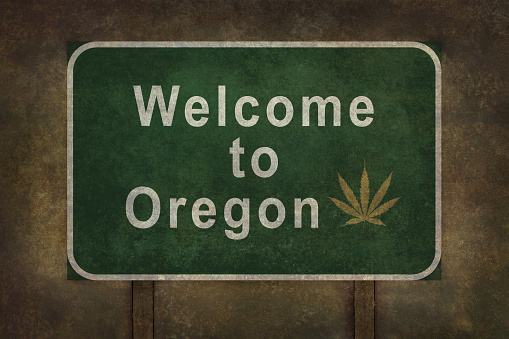 Welcome to Oregon road sign illustration with distressed ominous background and a cannabis leaf insert