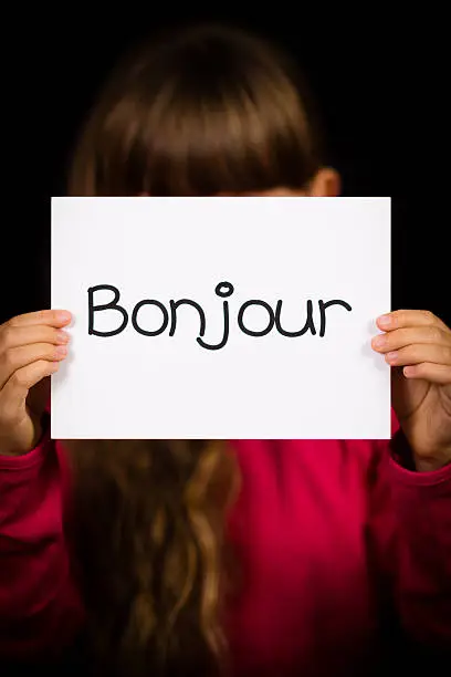 Studio shot of child holding a sign with French word Bonjour - Hello
