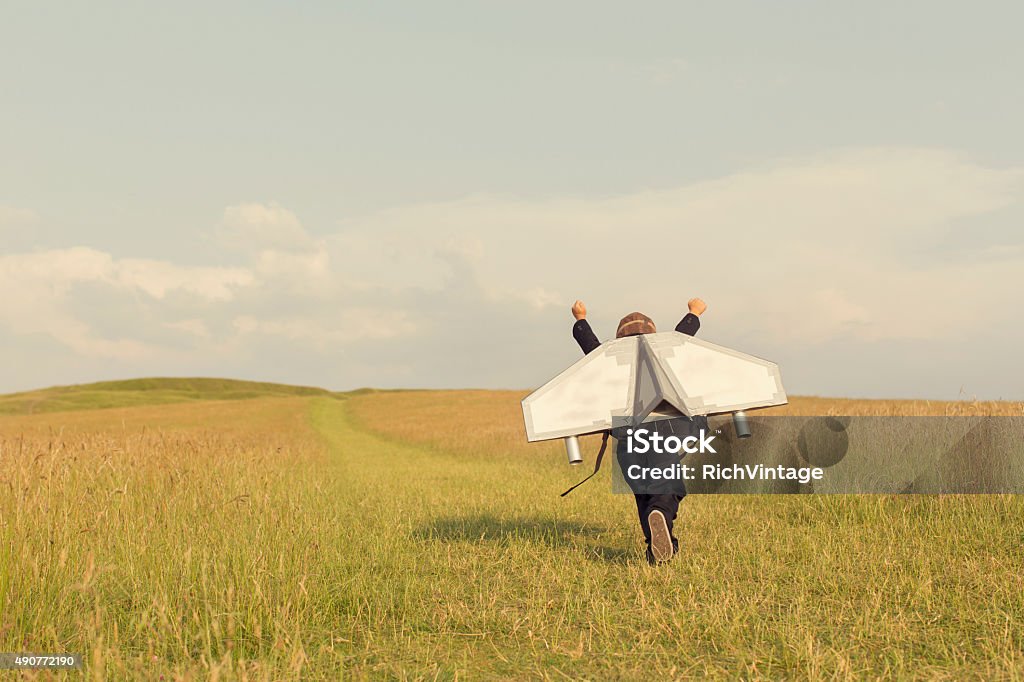 Young Business Boy Wearing Jetpack in England A young business boy is wearing a jetpack running through a grass field in the United Kingdom ready to take his business to the next level.  Child Stock Photo