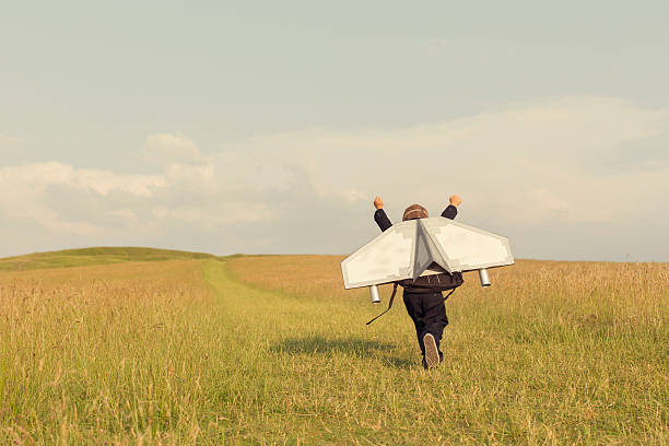 Young Business Boy Wearing Jetpack in England A young business boy is wearing a jetpack running through a grass field in the United Kingdom ready to take his business to the next level.  vintage people stock pictures, royalty-free photos & images