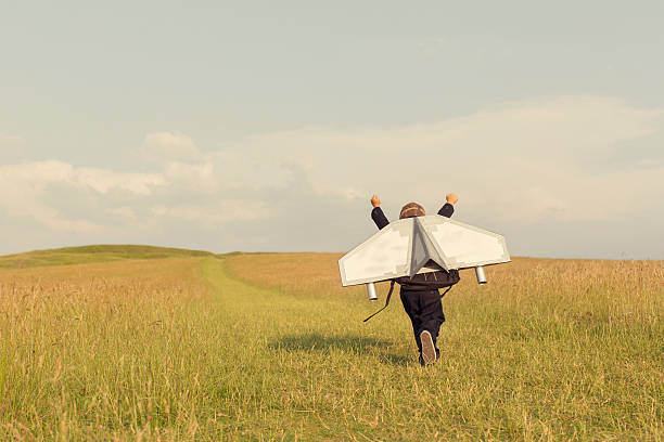 Young Business Boy Wearing Jetpack in England A young business boy is wearing a jetpack running through a grass field in the United Kingdom ready to take his business to the next level.  imagination stock pictures, royalty-free photos & images