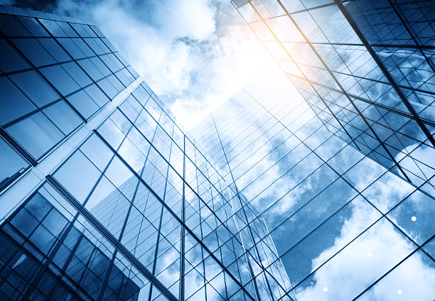 view of a contemporary glass skyscraper reflecting the blue sky - buildings stockfoto's en -beelden