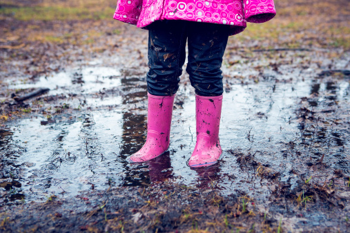 four-years-old is dancing in the middle of puddle