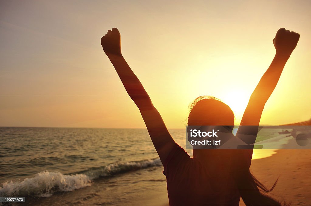 cheering woman open arms to sunset at seaside back of fitness woman open arms to sunset  at seaside One Woman Only Stock Photo