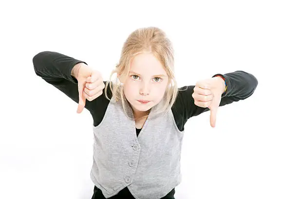 young girl in studio with both thumbs down against white background