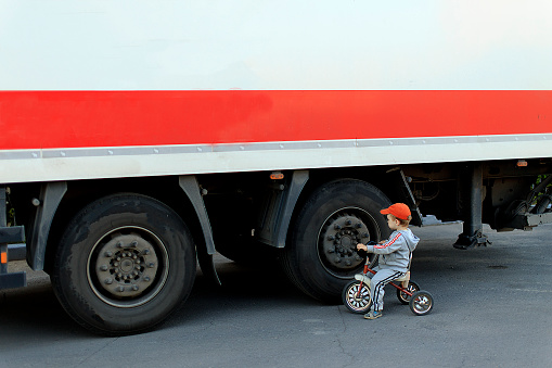 boy on a bicycle rode out on the roadway next to a large truck