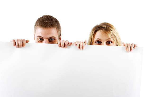 couple peeking out from behind the booth stock photo