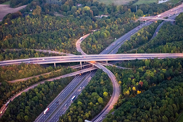 M25 Motorway interchange Sinuous curves of M25 motorway interchange at dusk, the street lights are on and cars are travelling along the 4 layer elevated jmajor road junction. overpass road stock pictures, royalty-free photos & images