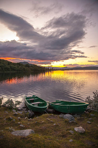 istock Sunset over a calm Norwegian  lake with boat on beach. 490782392