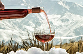 Glass and bottle of rosé wine on snow