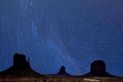 Night view of the Monument Valley area, at the Arizona and Utah border. Stars appear rotating around the North Star during long time night sky exposure.