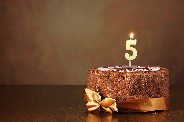 istock Birthday chocolate cake with burning candle as a number five 490784110
