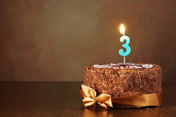 istock Birthday chocolate cake with burning candle as a number three 490784334