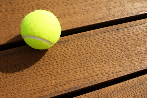 It is a tennis ball placed on the wood deck.