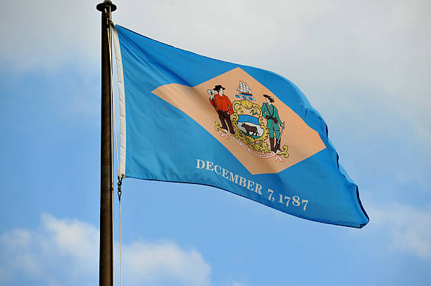 Delaware Flag Delaware Flag flying in the wind with beautiful sky on the background. us state flag stock pictures, royalty-free photos & images