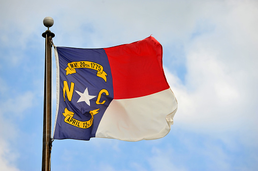 North Carolina Flag flying in the wind with beautiful sky on the background.