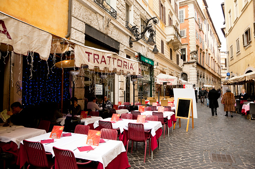 Rome, Italy -- January 1, 2013: Street of Rome with many restaurants and shops, people are dining at trattoria \