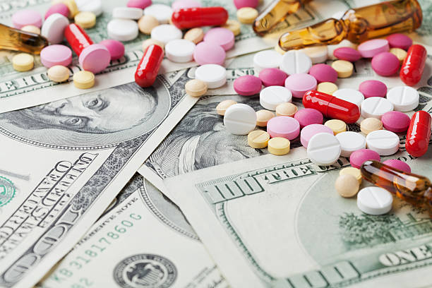 cost medicinal product and treatment concept, pills tablets with cash stock photo