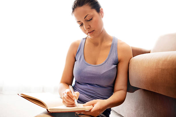 istock Young woman writing in a notebook at home. 490815540