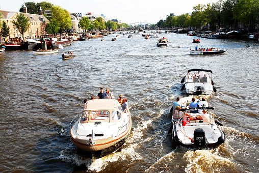Amsterdam, Netherlands- August 20, 2015: People sailing on recreational luxury boats the Amstel river during the SAIL Amsterdam weekend.