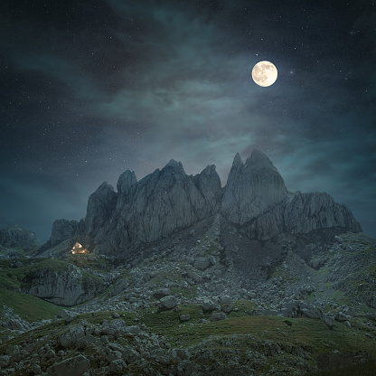 Mystical peaks with moon and mountain house at night.