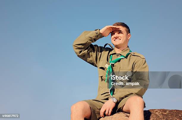 Boy Scout Sentado En Rock Frente Al Campo Foto de stock y más banco de imágenes de Boy scout - Boy scout, 2015, Actividad