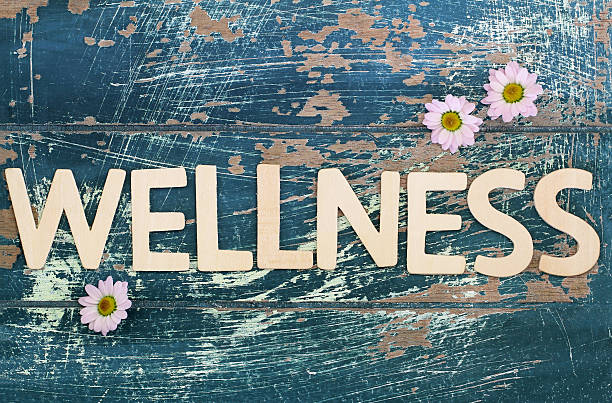 istock Wellness written on rustic wooden surface and pink daisy flowers 490818570