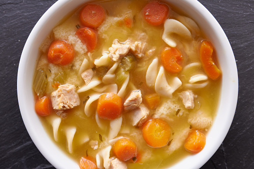 photo of a bowl of chicken noodle soup shot top down close up