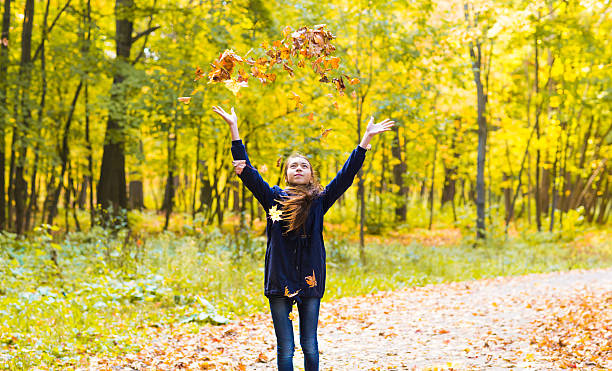 istock happy girl  walks in autumn park throws up fallen maple 490820934