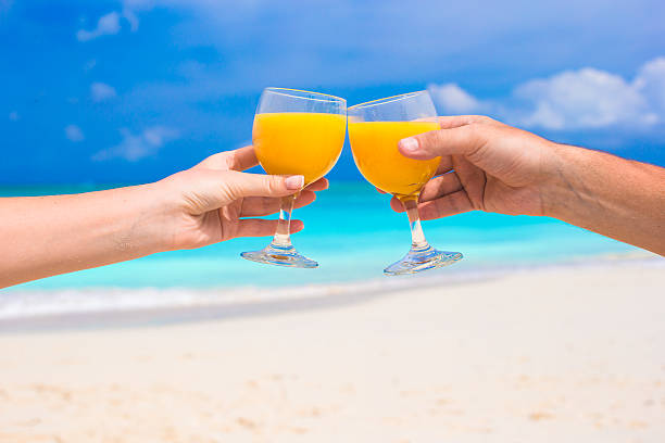 istock Two hands hold glasses with orange juice background blue sky 490821889