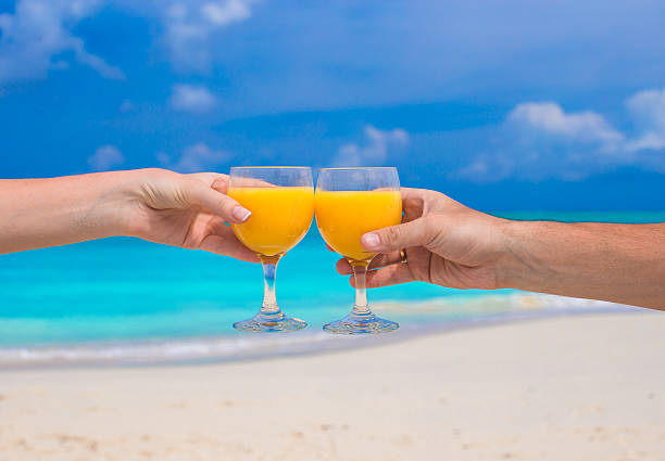 istock Two hands hold glasses with orange juice background blue sky 490821895