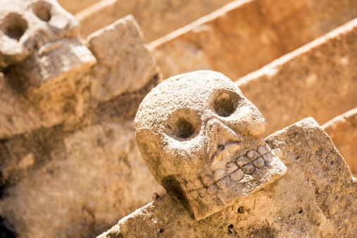 Closeup of scary Mexican stone skulls with stairs in the background