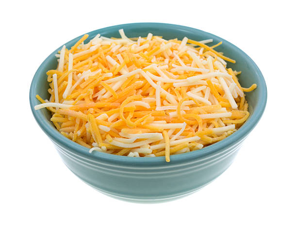 Variety of cheeses in a small bowl A small bowl filled with shredded white cheddar, sharp cheddar and mild cheddar cheeses isolated on a white background. shredded photos stock pictures, royalty-free photos & images