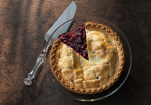 Berry pie with slice out on moody material background