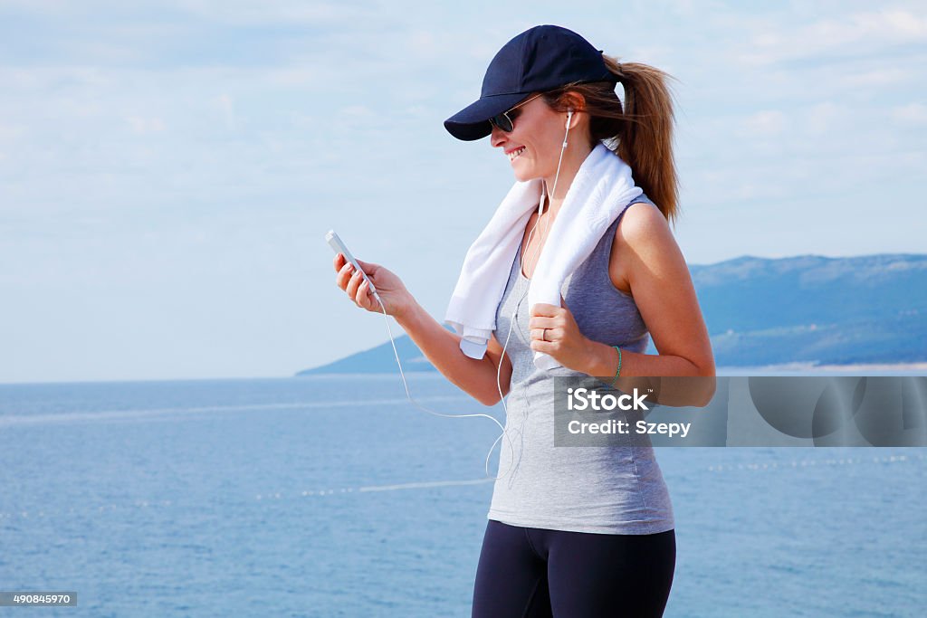 After workout Portrait of middle age woman standing at the beach and relaxing after workout. Sporty female listening music and smiling. 2015 Stock Photo