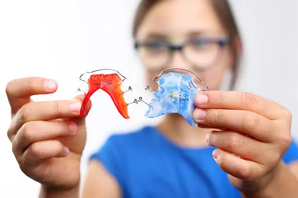 Pretty girl with colored orthodontic appliance .