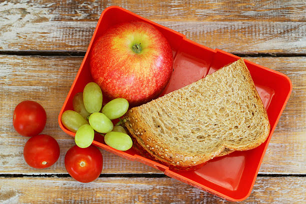 lunchbox mit braun brot sandwich, apfel, traube und tomaten - lunch box lunch sandwich green stock-fotos und bilder