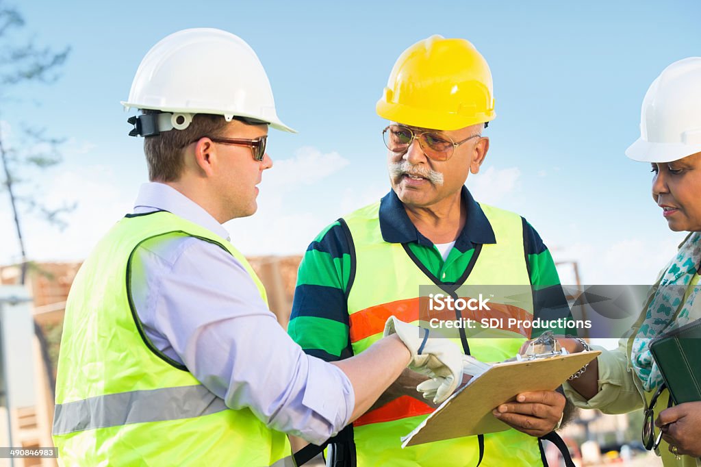 Costruttori discutendo la costruzione di lavoro sito - Foto stock royalty-free di Adulto