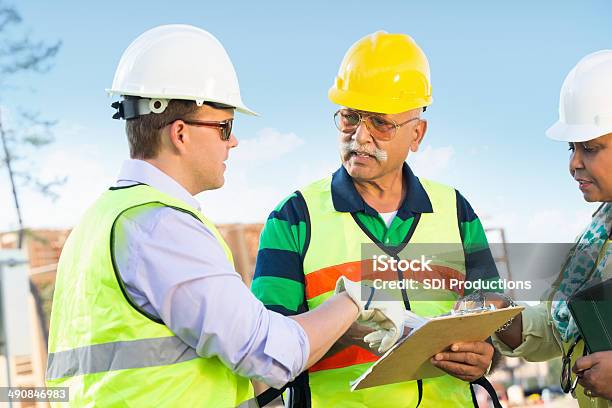 Construtores De Discutir No Local De Trabalho De Construção - Fotografias de stock e mais imagens de Adulto