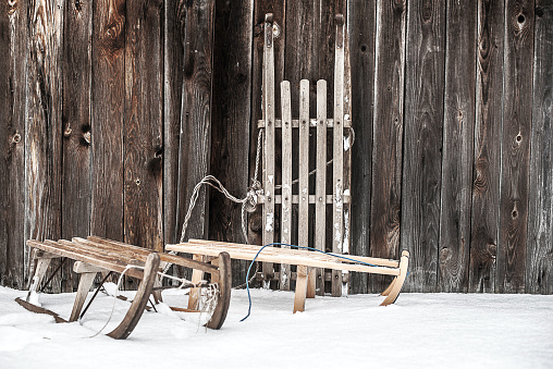 three old sleighs on wooden wall