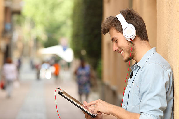 istock Man using a tablet with headphones on the street 490847182