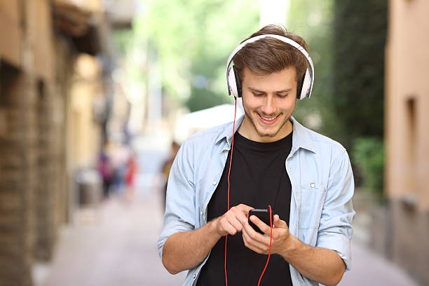 istock Guy walking and using a smart phone with headphones 490847788