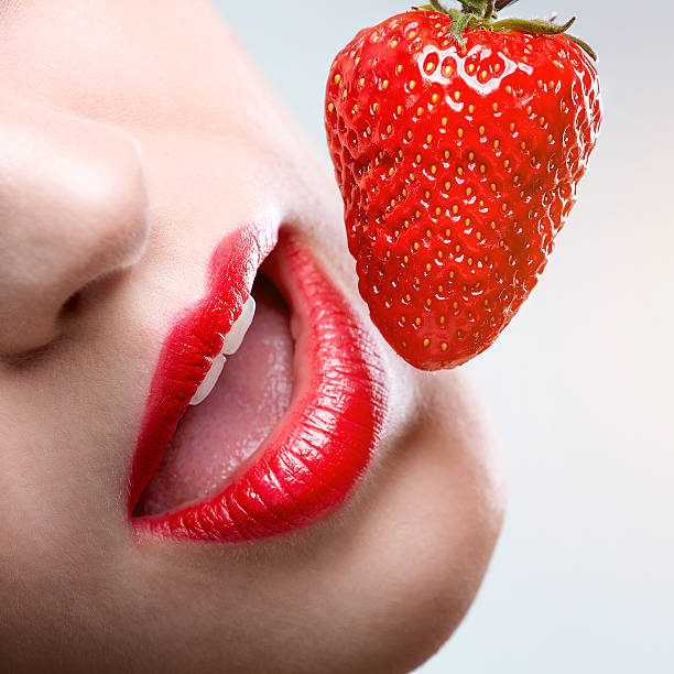 istock Female red lips, eating strawberries 490847989