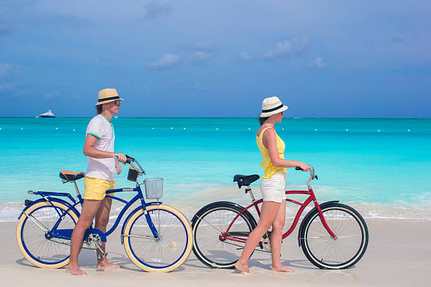 istock Young happy couple riding bikes on white sandy beach 490848689