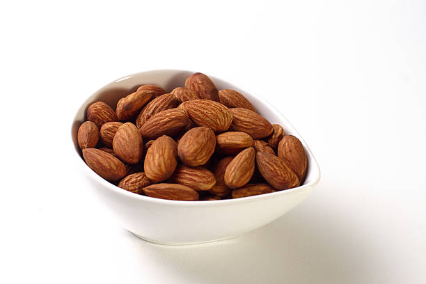 istock almonds and wooden spoon on white background 490848798