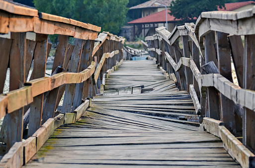 Closeup of a deformed and dilapidated wooden bridge over the river